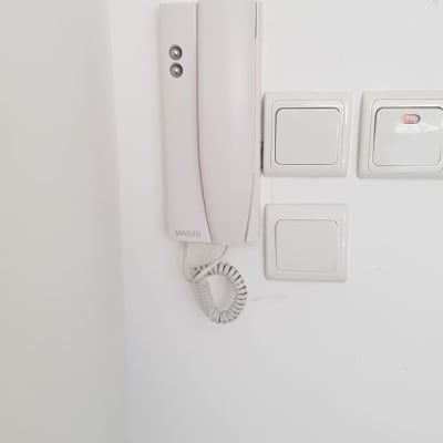 אינטרקום לבן עם כפתורים על קיר לבן