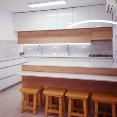 מטבח מודרני עם ארונות לבנים וכיסאות עץ