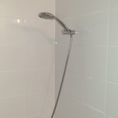 ראש מקלחת מותקן על קיר אריחים לבנים