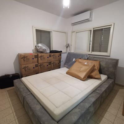 חדר שינה עם קופסאות קרטון ומיטה אפורה