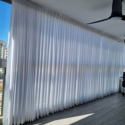 וילונות לבנים תלויים על חלון גדול