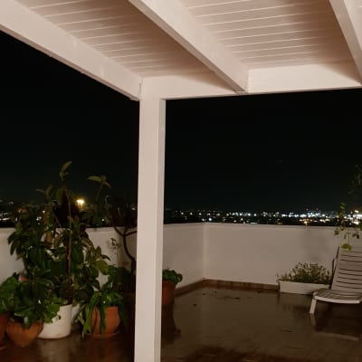 מרפסת עץ עם עציצים ותאורה לילית