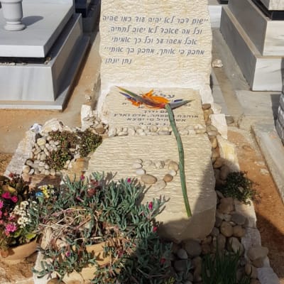 מצבות עם כיתוב בעברית ופרחים על הקבר