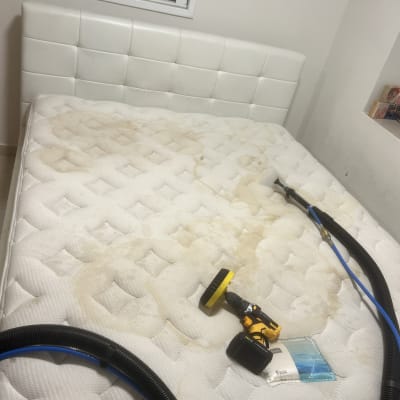 מזרן עם כתמים, מכונת ניקוי צהובה וצינור שחור