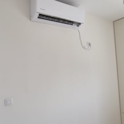 מזגן מותקן על קיר לבן עם כבל חשמל