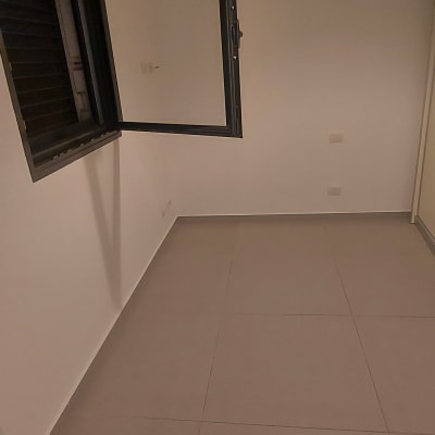 חדר ריק עם קירות לבנים ורצפת אריחים אפורה