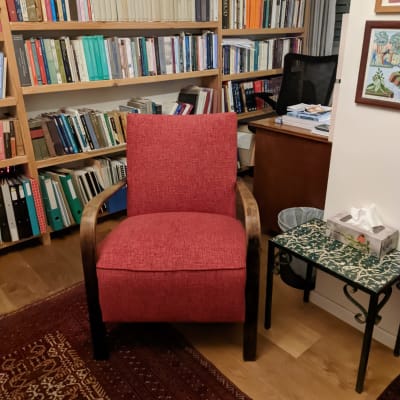 כורסה אדומה עם ריפוד על שטיח בחדר עבודה