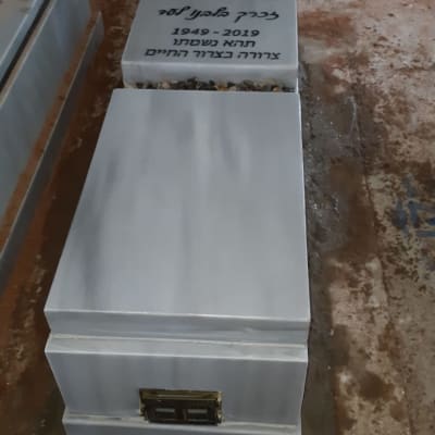 מצבה עם כיתוב בעברית ואבנים קטנות