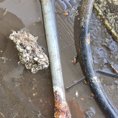 צינור חלוד עם חוטי מתכת על רצפה רטובה