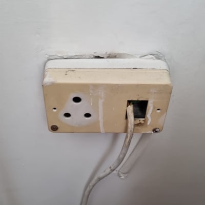 שקע חשמל ישן עם חוטים חשופים בקיר