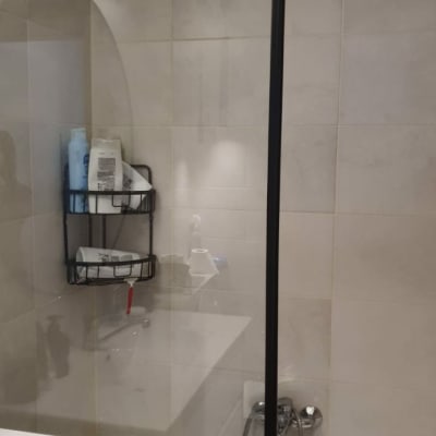 מקלחת עם מדף מתכת, בקבוקי שמפו וסבון