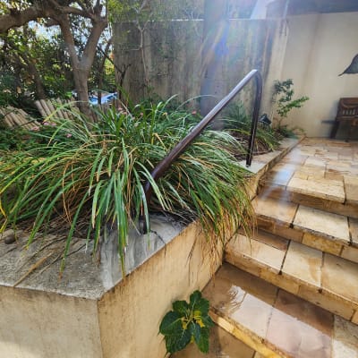 מעקה מתכת שחור ליד מדרגות אבן בגינה