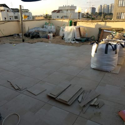 עבודת ריצוף חוץ באריחי גרניט פורצלן במרפסת גג במהלך שיפוץ