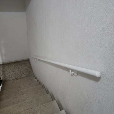 מעקה לבן מותקן על קיר מדרגות