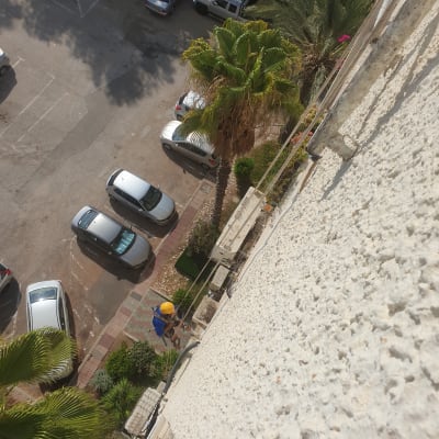 אדם עם קסדה צהובה עובד על קיר בניין