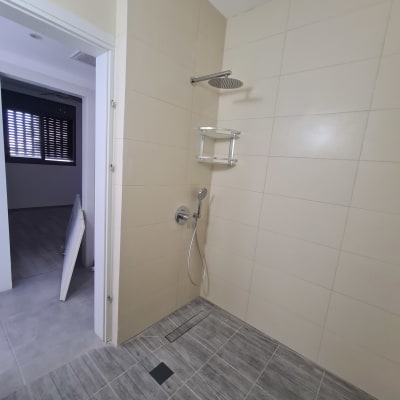 מקלחת עם אריחים חדשים ומדף מתכת