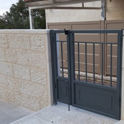 שער מתכת אפור על קיר אבן חיצוני