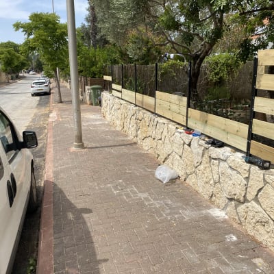 גדר עץ חדשה על קיר אבן בגינה