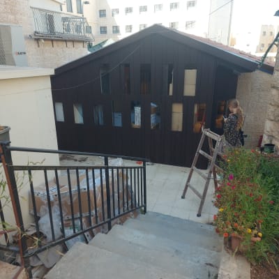 מבנה עץ עם חלונות, סולם וארגזים בחצר