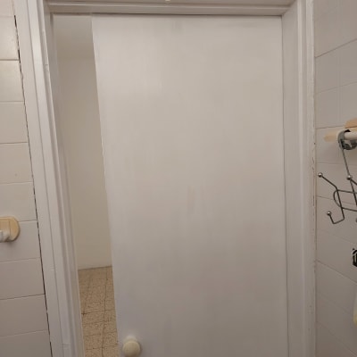 דלת לבנה עם ידית עגולה וחוט חשמל חשוף