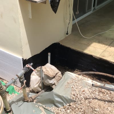 אדם עובד על איטום קיר חיצוני עם חומר שחור