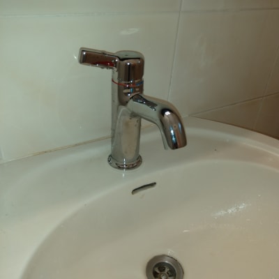 ברז כרום על כיור לבן עם ניקוז