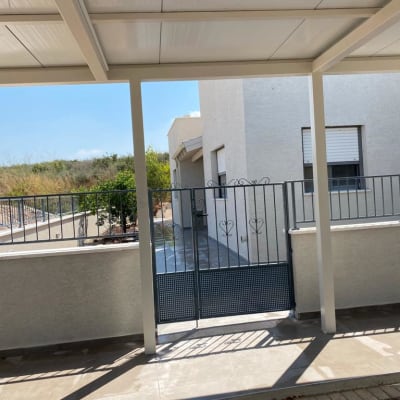 גדר מתכת עם שער תחת פרגולה לבנה