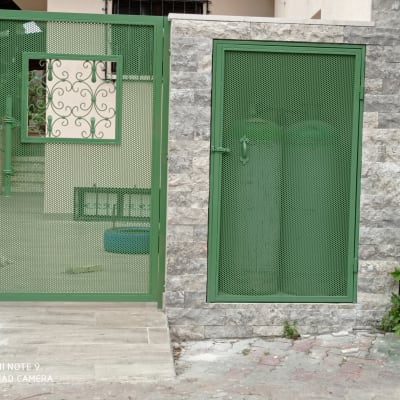 שער מתכת ירוק עם עיטורים על רקע קיר אבן אפור