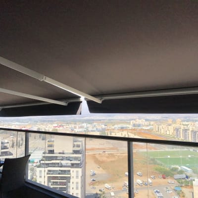 סוככים כהים מותקנים על מרפסת עם נוף עירוני