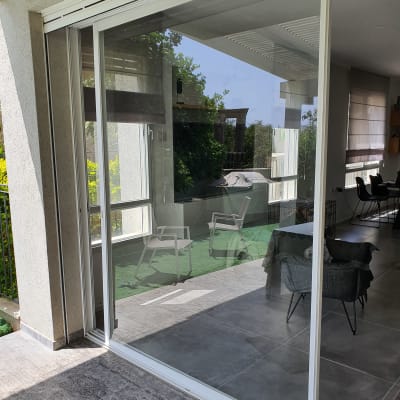 דלת זכוכית גדולה עם מסגרת לבנה במרפסת