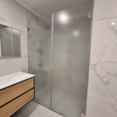 דלת זכוכית חלבית עם ידית מתכת בחדר רחצה