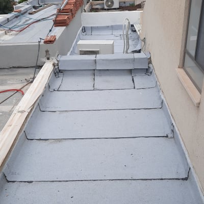 גג אטום ביריעות ביטומניות אפורות עם חיבורים שחורים