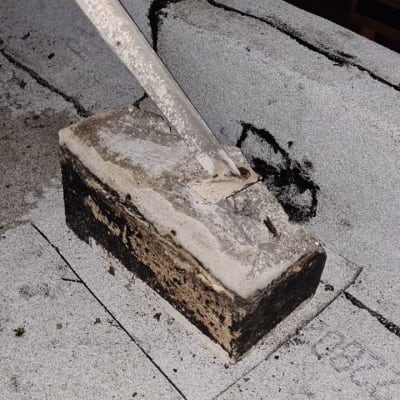 חומר איטום שחור על גג בטון עם בלוק מתכת