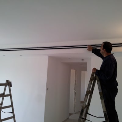 אדם על סולם מתקין מזגן בתקרה