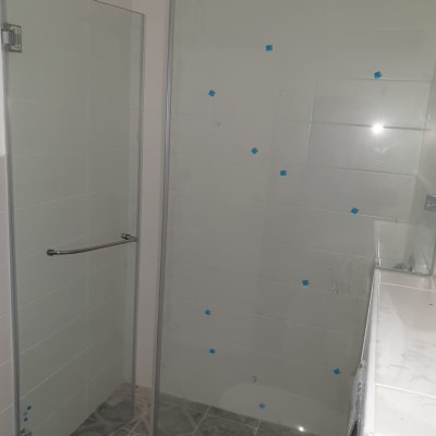 מקלחון זכוכית עם אריחים לבנים ורצפת קרמיקה אפורה