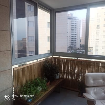 חלונות אלומיניום במרפסת סגורה עם נוף עירוני