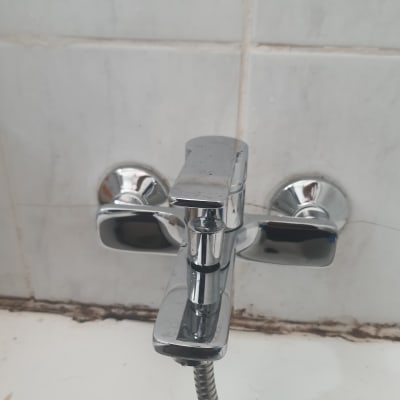 ברז כרום עם צינור גמיש על קיר אריחים