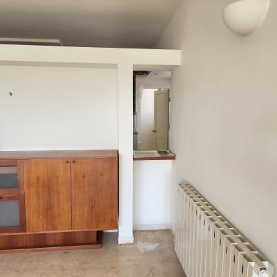 קיר צבוע בלבן עם רהיט עץ ומטאטא