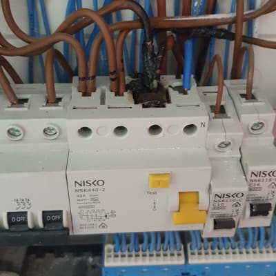 לוח חשמל עם חוטים חומים וכחולים ומפסקי חשמל