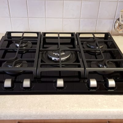 כיריים גז שחורות עם חמישה מבערים וכפתורי שליטה כסופים