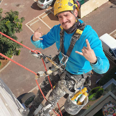 אדם עם קסדה ורתמה על חבל, מחזיק דלי עם חומרי איטום