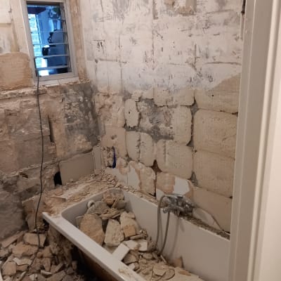 חדר אמבטיה בשיפוץ עם קירות חשופים ופסולת בנייה