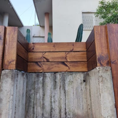 גדר עץ חומה על קיר בטון בגינה