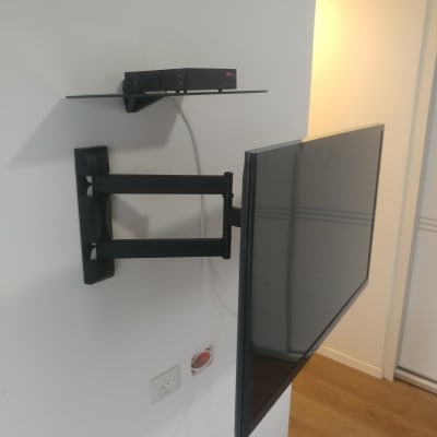 טלוויזיה מותקנת על זרוע קיר עם מדף עליון