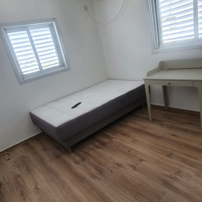 חדר עם רצפת עץ ומיטה מסודרת