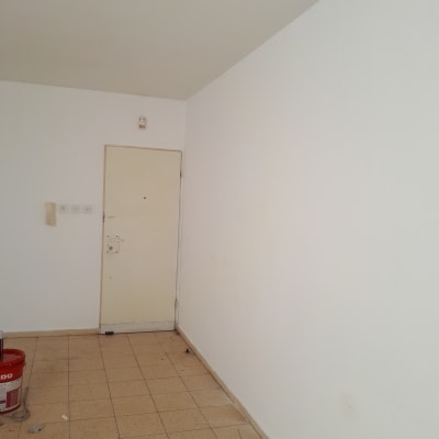 דלי צבע אדום על רצפה ליד קיר לבן