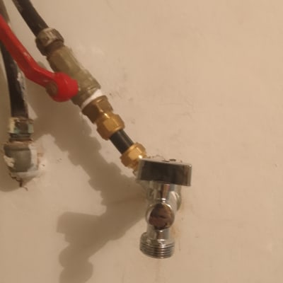 ברז מתכת עם צינור וחיבורים על קיר