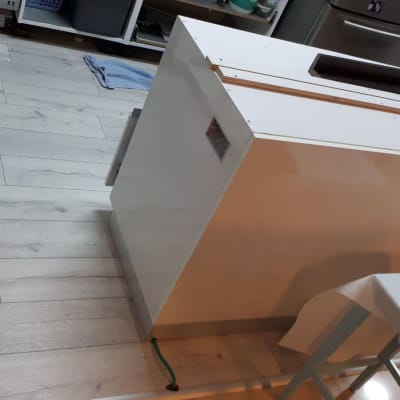 ארון לבן בתהליך הרכבה על רצפת עץ