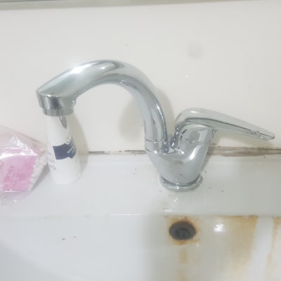 ברז כרום עם כתמי חלודה בכיור לבן