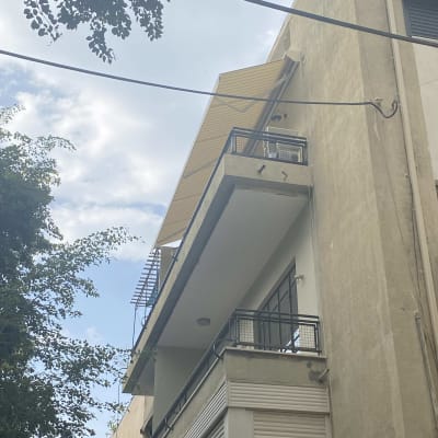 סוכך צהוב מותקן מעל מרפסת בקומה עליונה